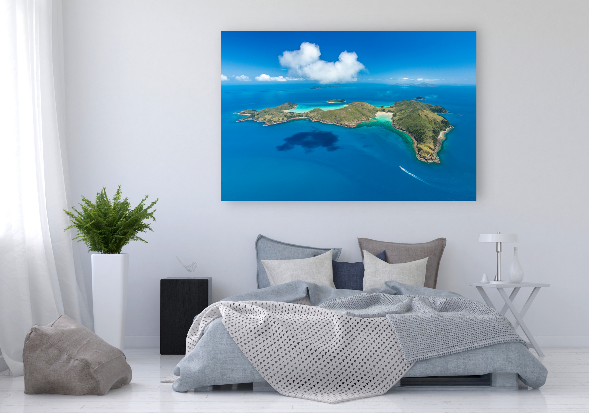 green mountainous island surrounded by green sandy beaches with clouds above casting a shadow over the water