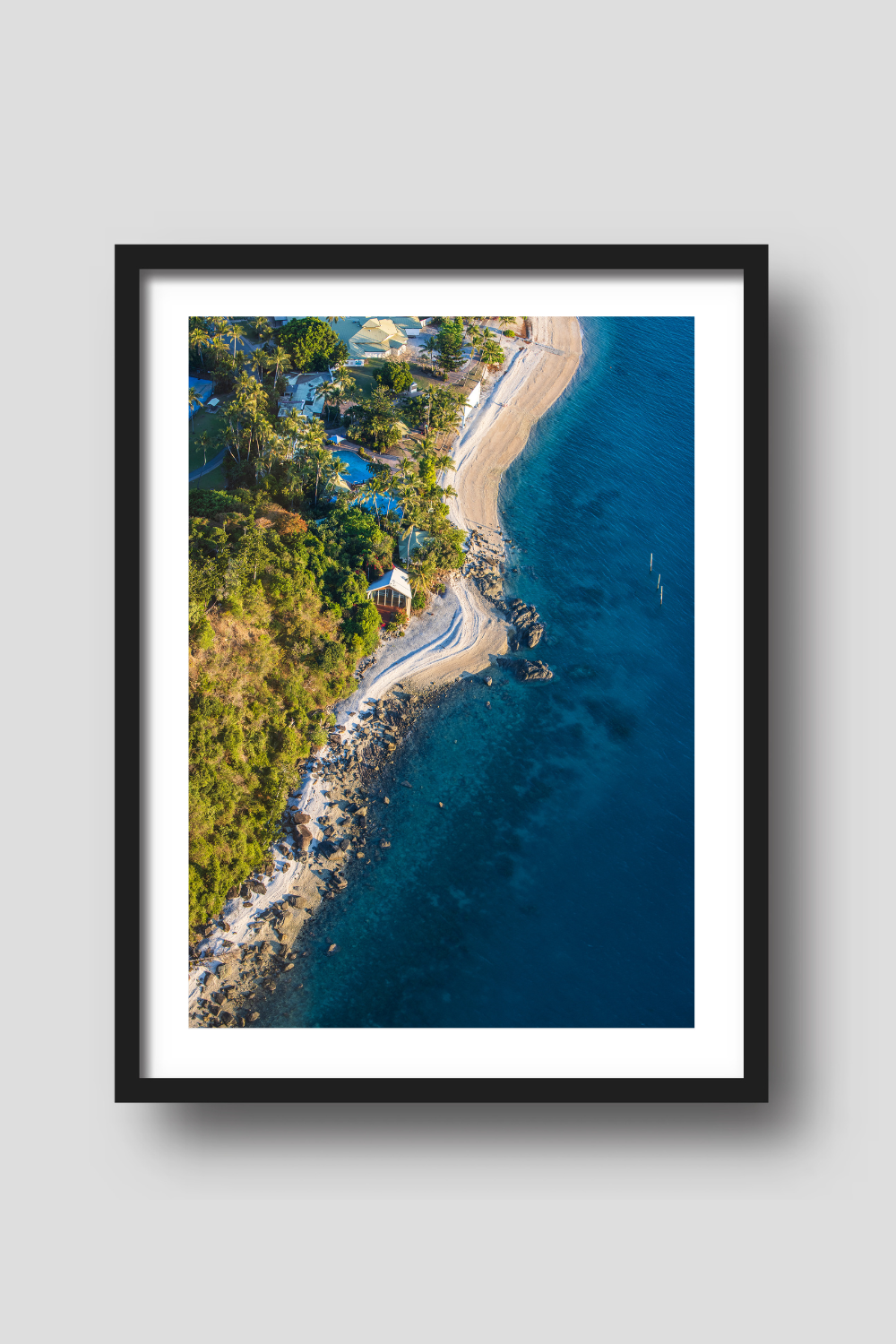 from above coastline with water on the right rocky sand beach, buildings and a chapel on the shoreline