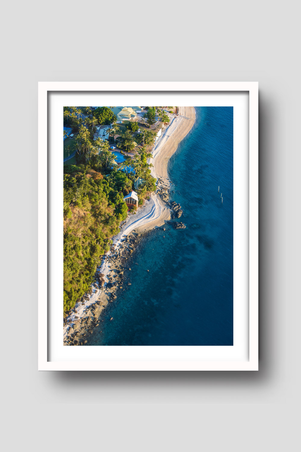 from above coastline with water on the right rocky sand beach, buildings and a chapel on the shoreline