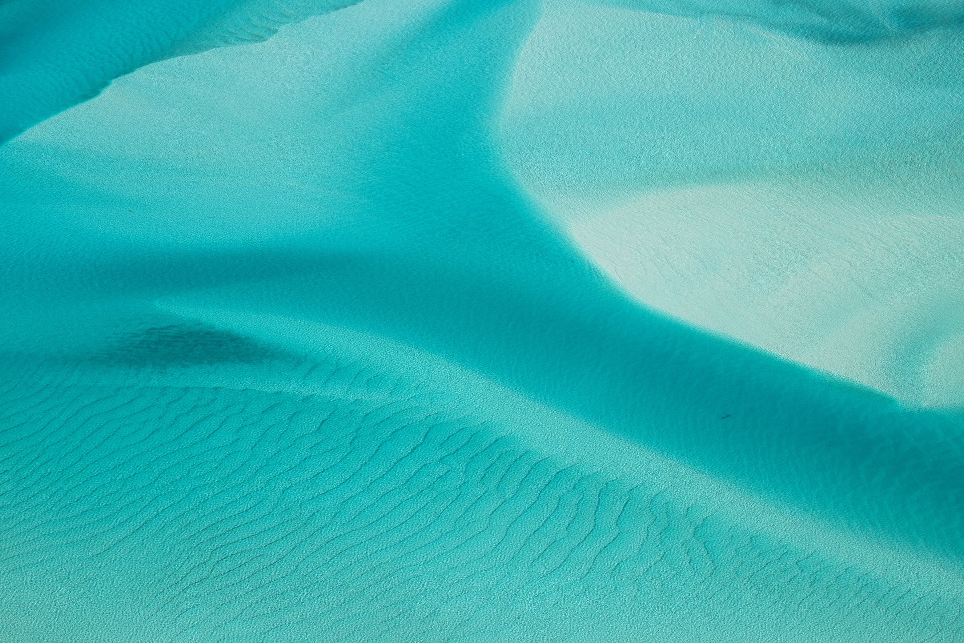 close up ripple of turquise waters amongst white sand