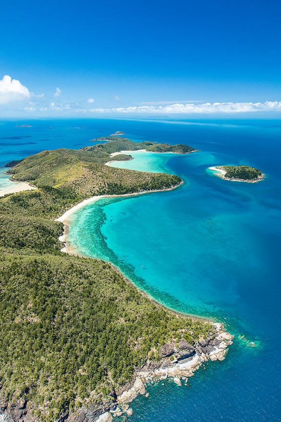 aerial shot of an island dotted with bays of coral and sand