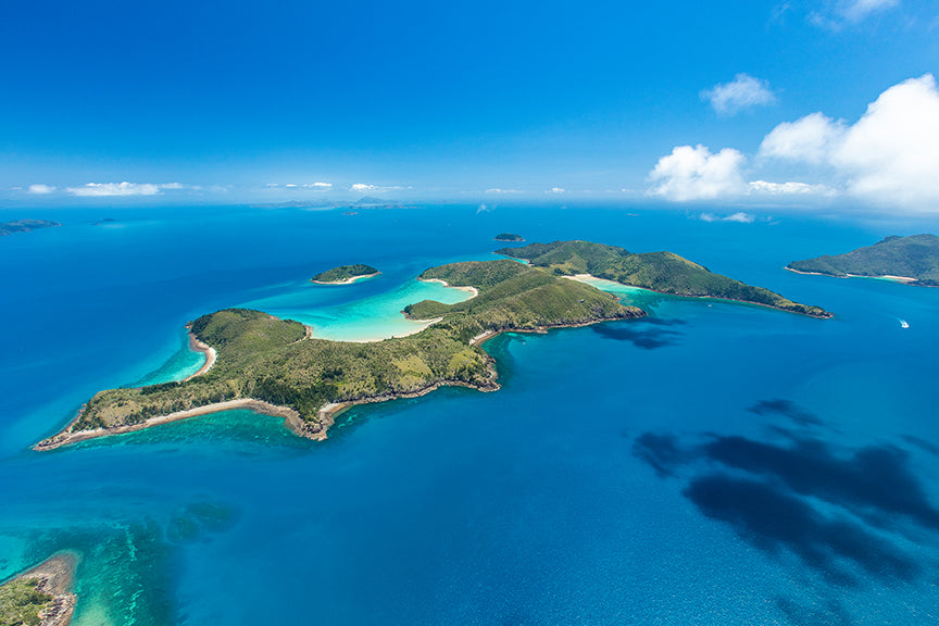 aerial of an island with bays of white sandy coral beaches
