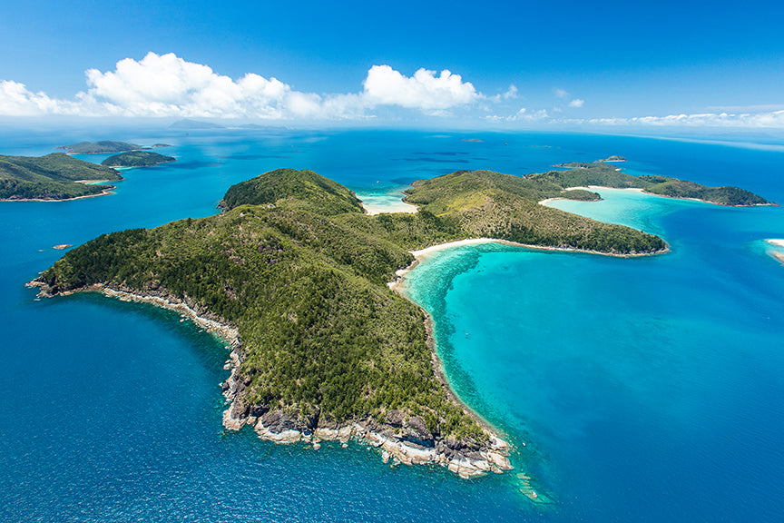 aerial of an island with bays of white sandy coral beaches and more islands in the background
