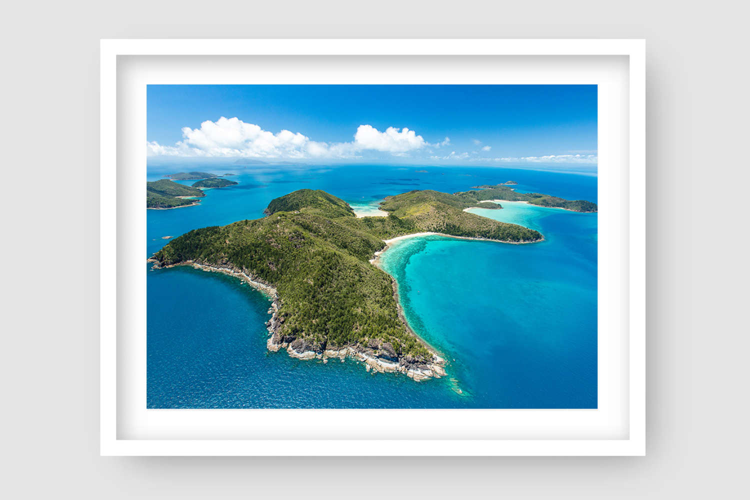 aerial of an island with bays of white sandy coral beaches and more islands in the background