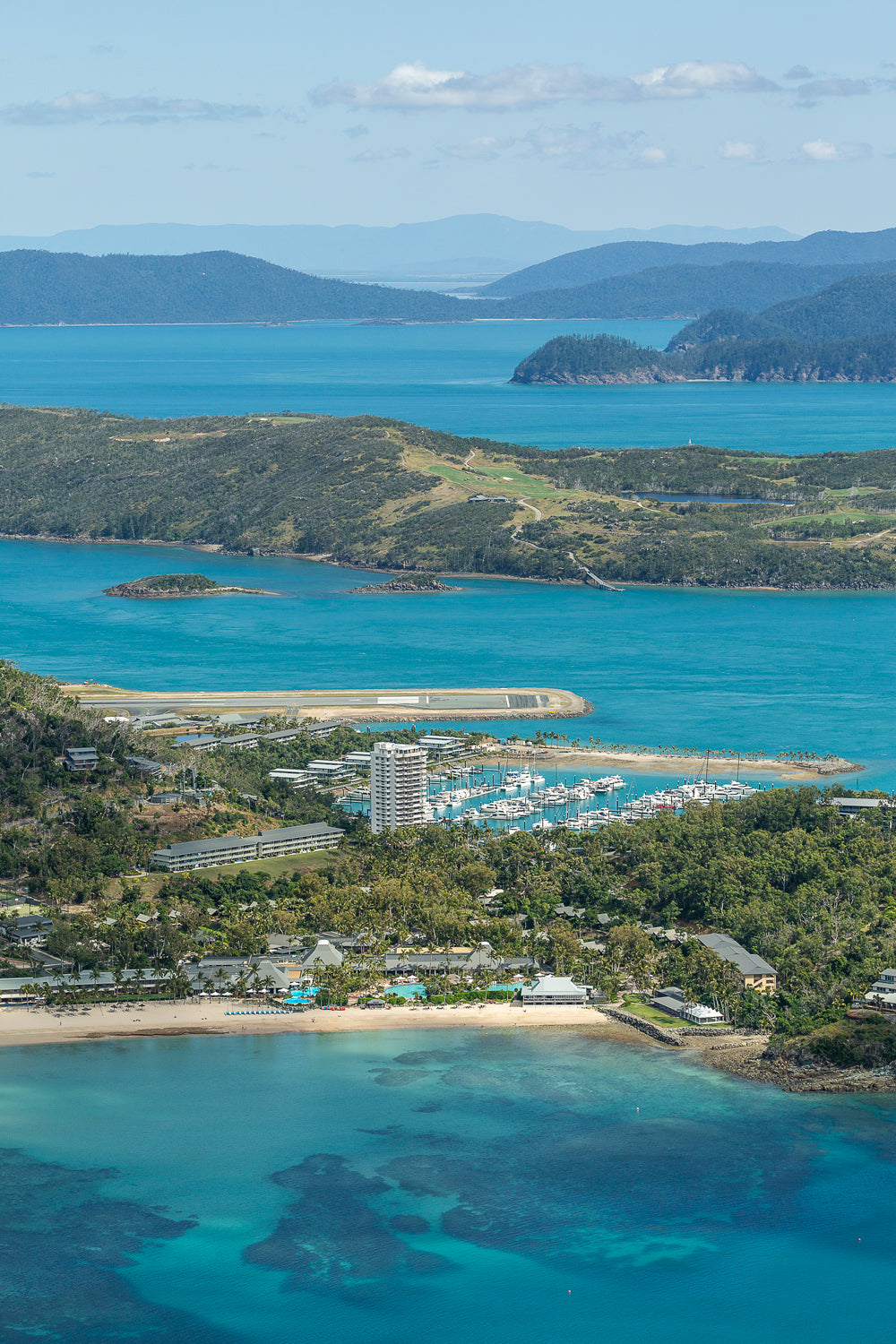 aerial close up of holiday island including a marina and airport and another island further back