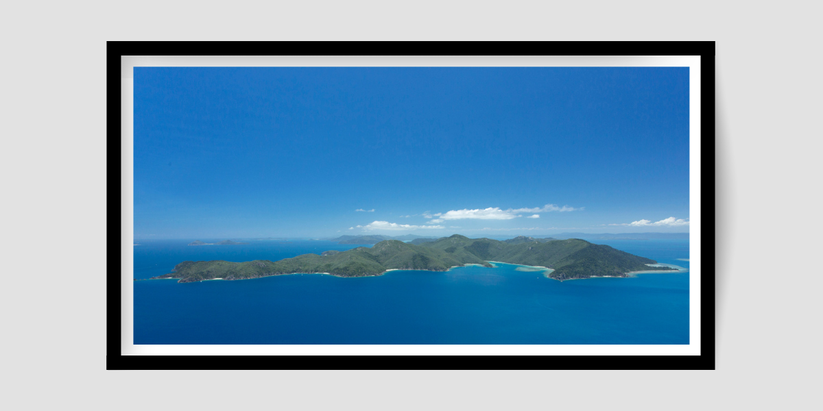 large island of green hills with blue sky and water all around