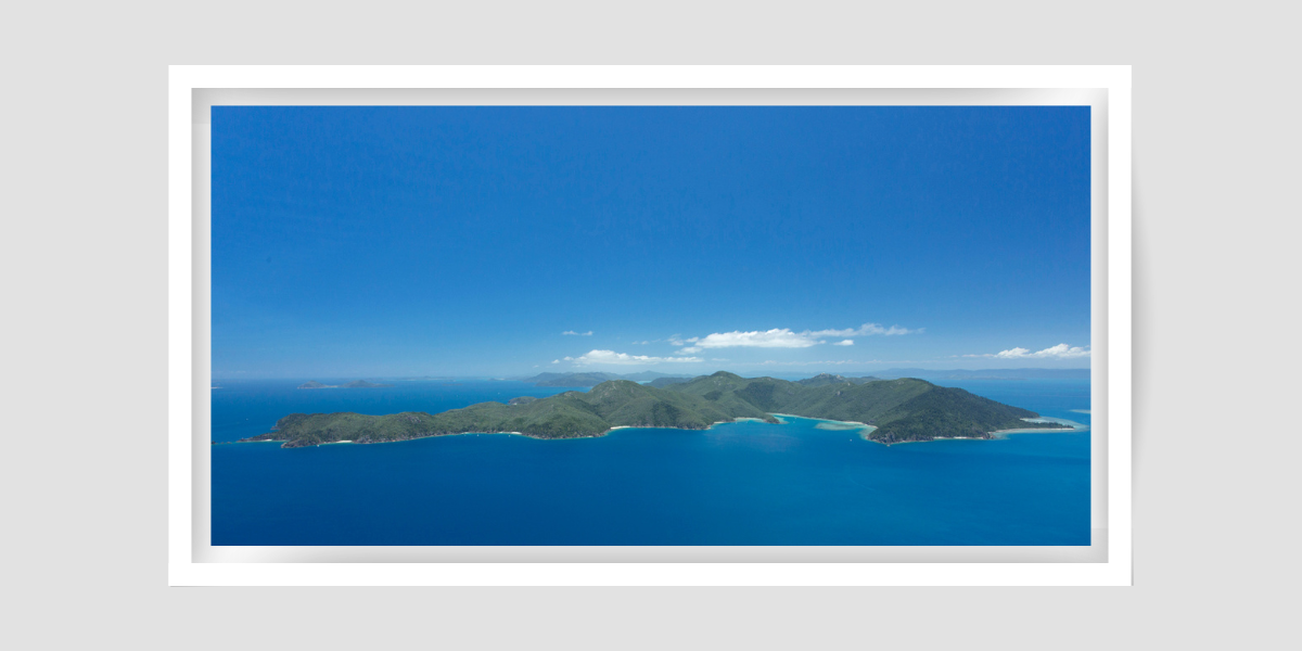 large island of green hills with blue sky and water all around