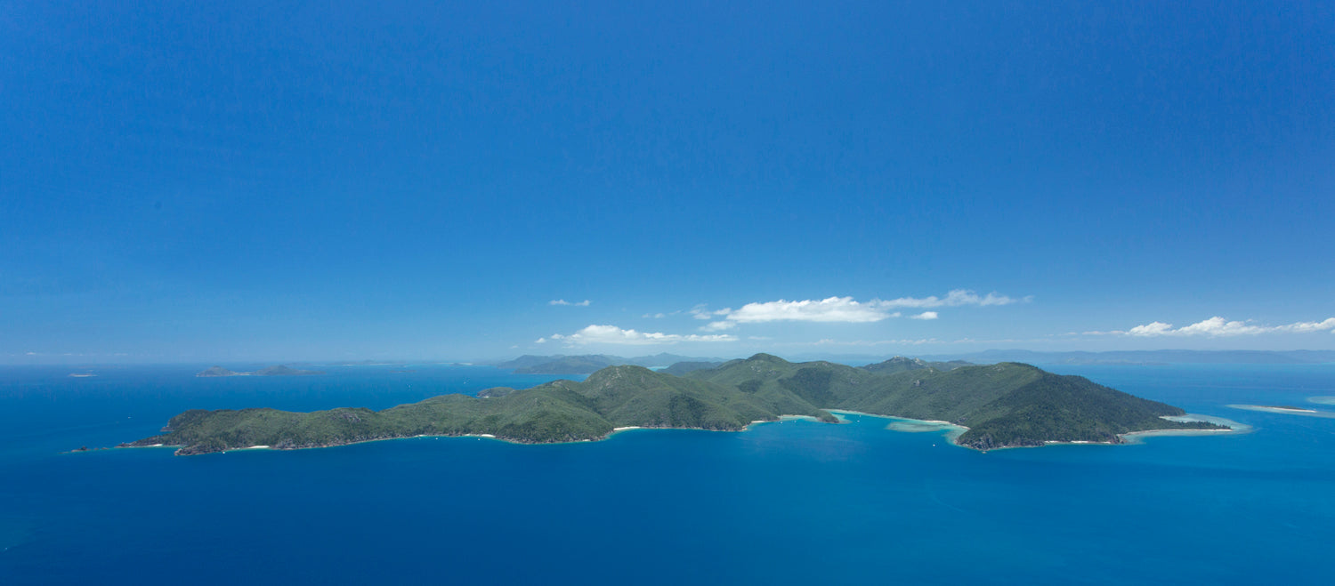 large island of green hills with blue sky and water all around