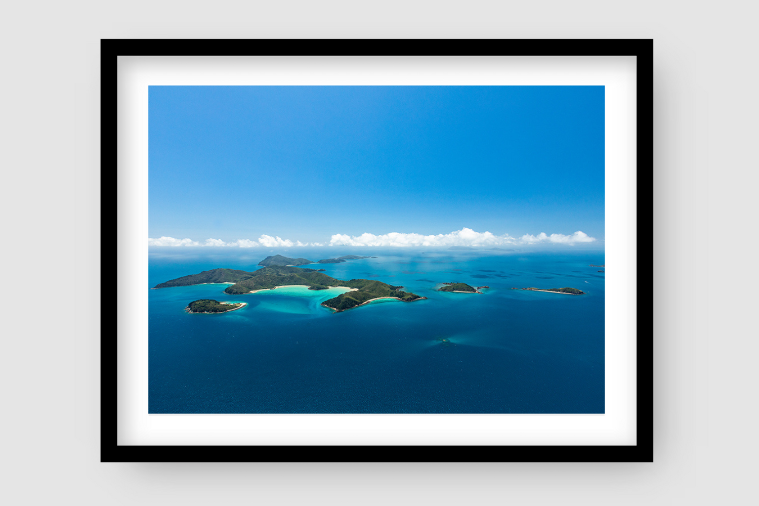collection of islands with large turquiose and white sandy bay clouds lining the horizon
