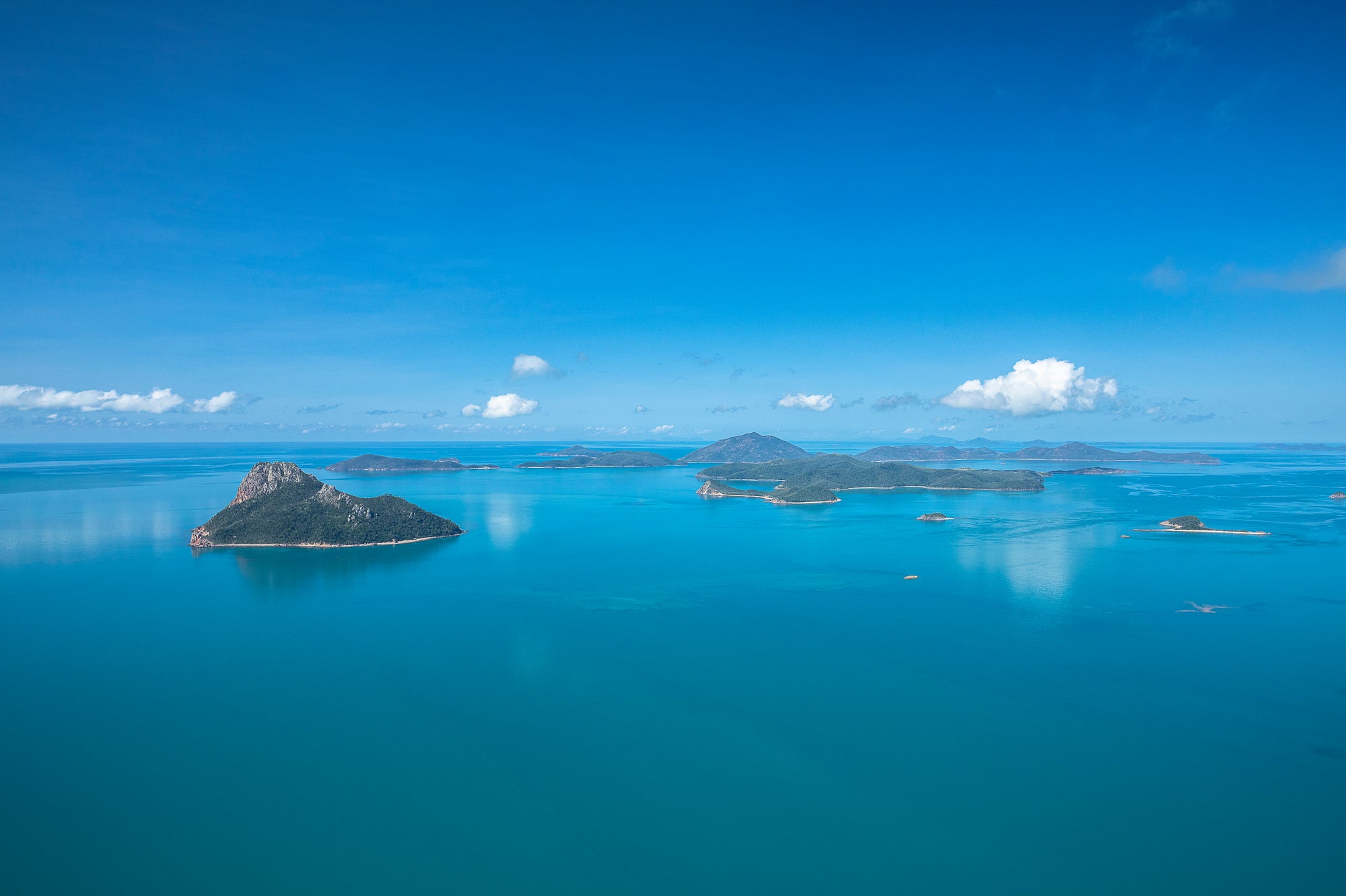 flat blue water below a clear blue sky with islands dotted about