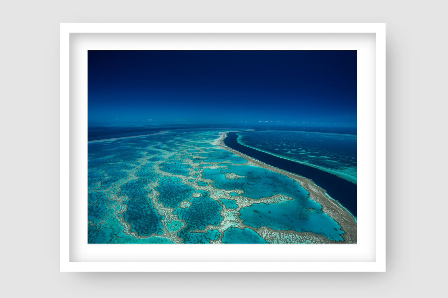 far and wide coral reef in blue and green colours with deep channel of water 