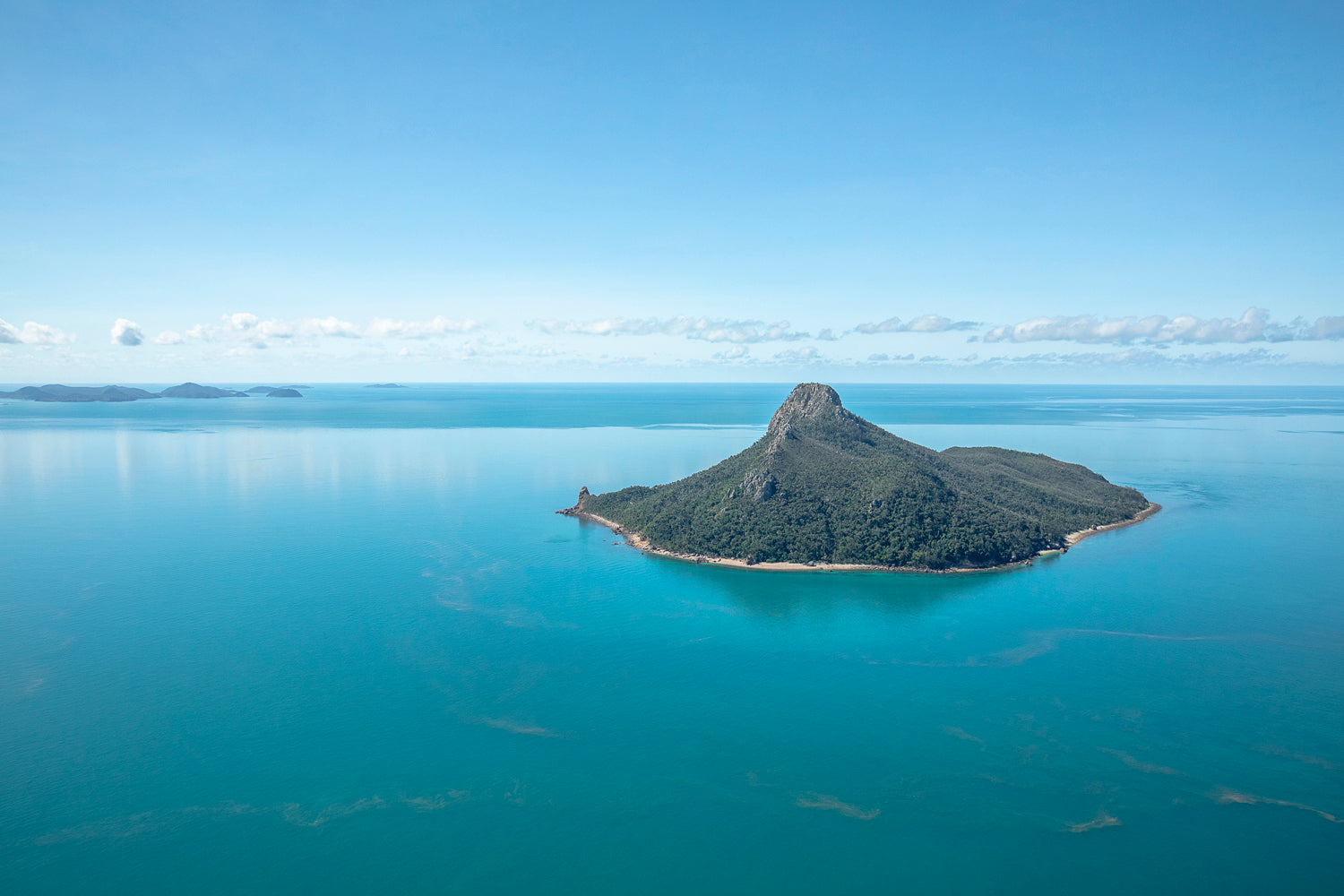 flat calm blue ocean waters surrounding a tall mountainous island