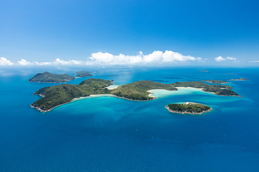 cluster of islands dotted with white sandy bays clouds lining the horizon
