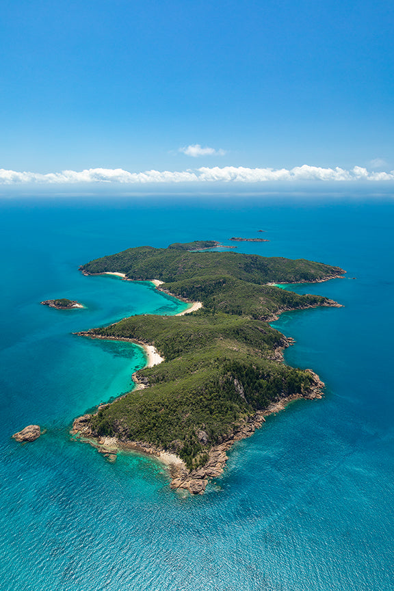 aerial of island with secluded white sandy bay and blue ocean surrounding
