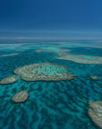 large archipelago of veiny coral reefs dotted about blue green ocean water