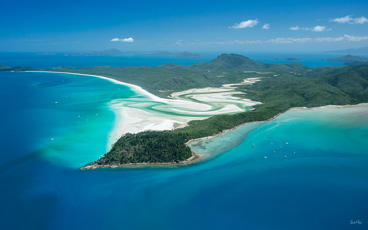 wide shot of a large island with a vertical waterfall of sand and water snaking out into the big blue ocean