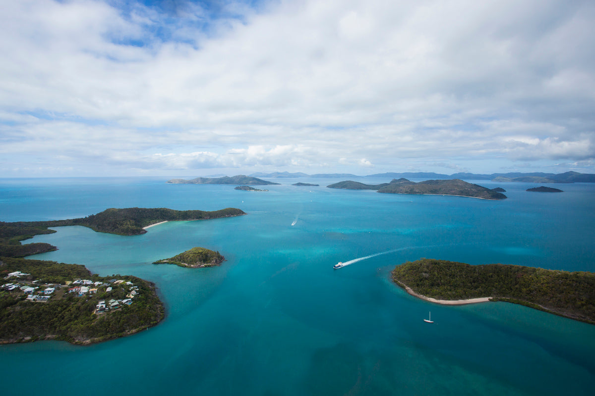 aerial of lush green islands and mainland with a couple of different vessels underway