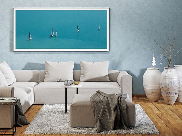5 sailing vessels with their sails raised in a line, one behind the other with blue ocean surrounding them