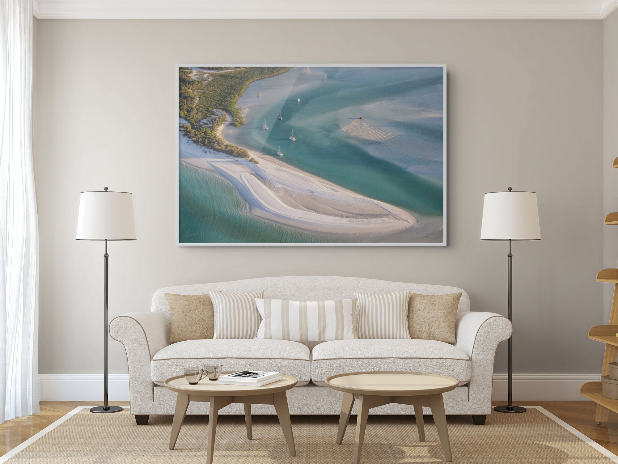Living room with a white sofa, coffee table, and two floor lamps. A large framed picture of a beach scene hangs on the wall.