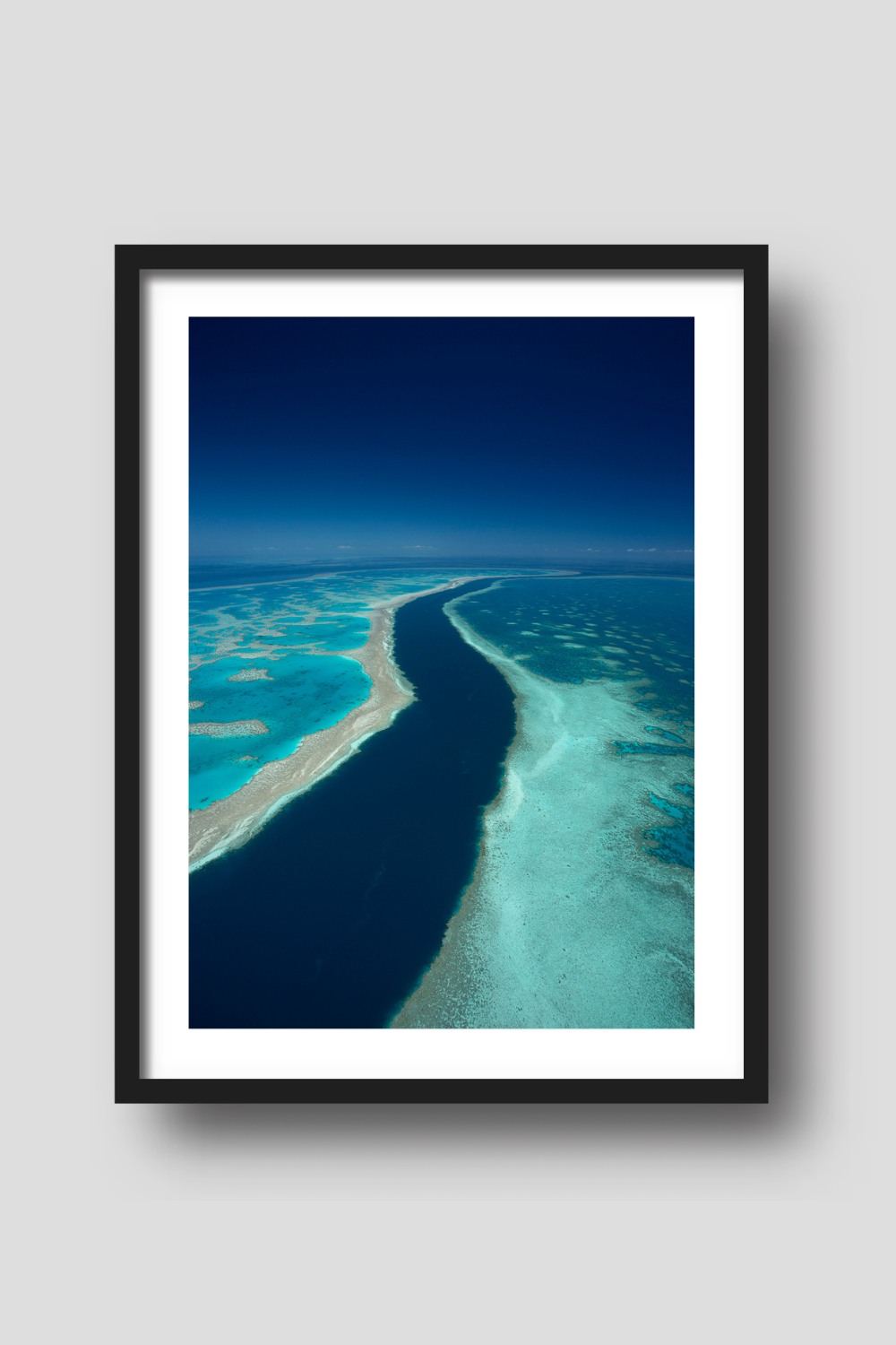 dark blue deep channel of water creating a river between green blue and brown fringing reef