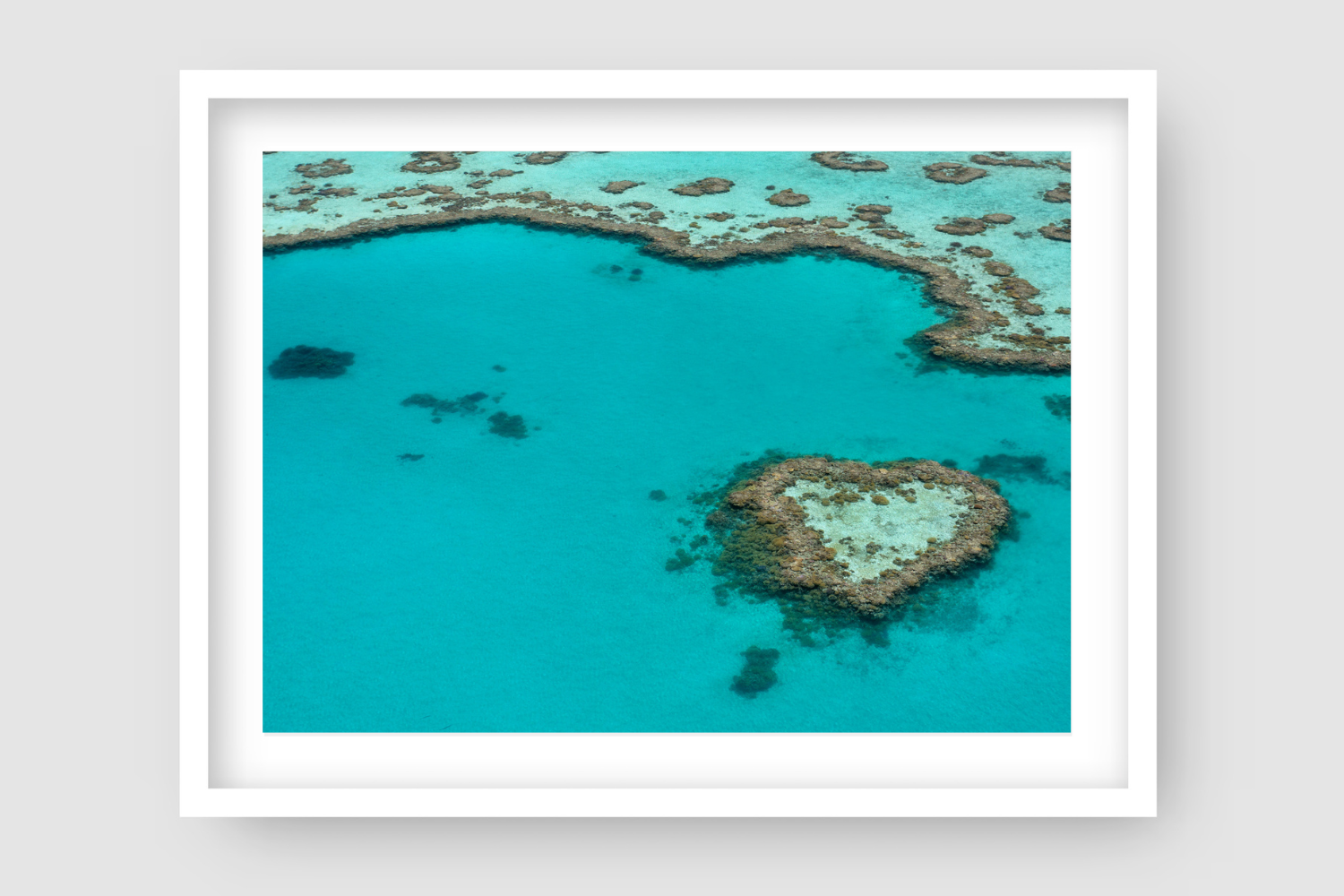 large heart shaped coral reef island surrounded by turquise water and more reef
