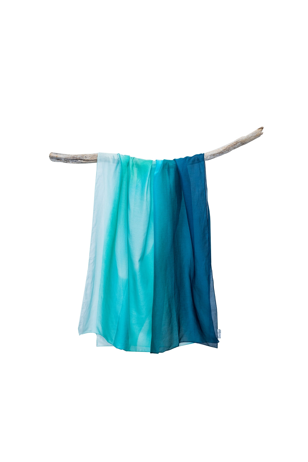 cotton silk sarong print of a small boat in the distance replicates a comet amongst the sand and blue green water swirling together