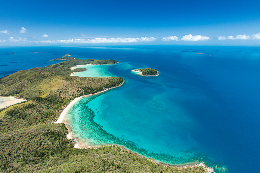 aerial shot of an island dotted with bays of coral and sand 