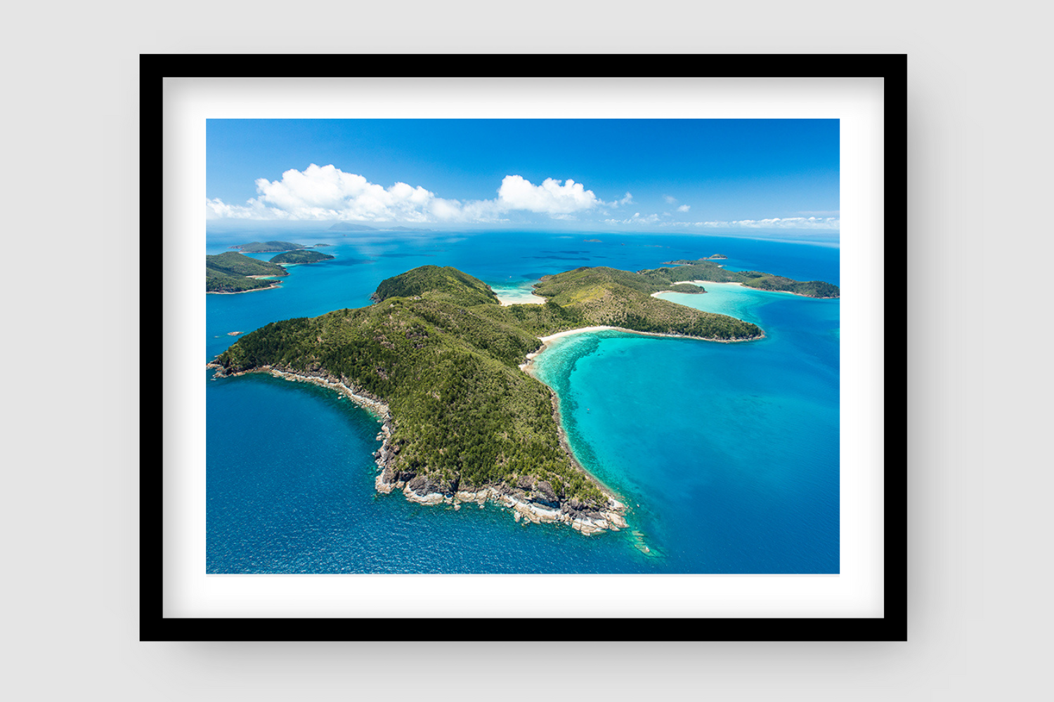 aerial of an island with bays of white sandy coral beaches and more islands in the background