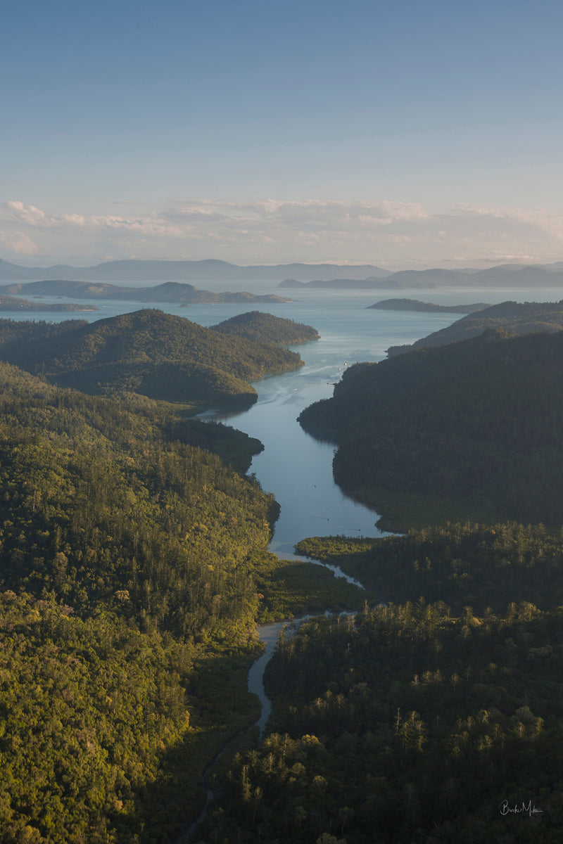 afternoon light setting over the hills of an island with a passage of water running down the middle