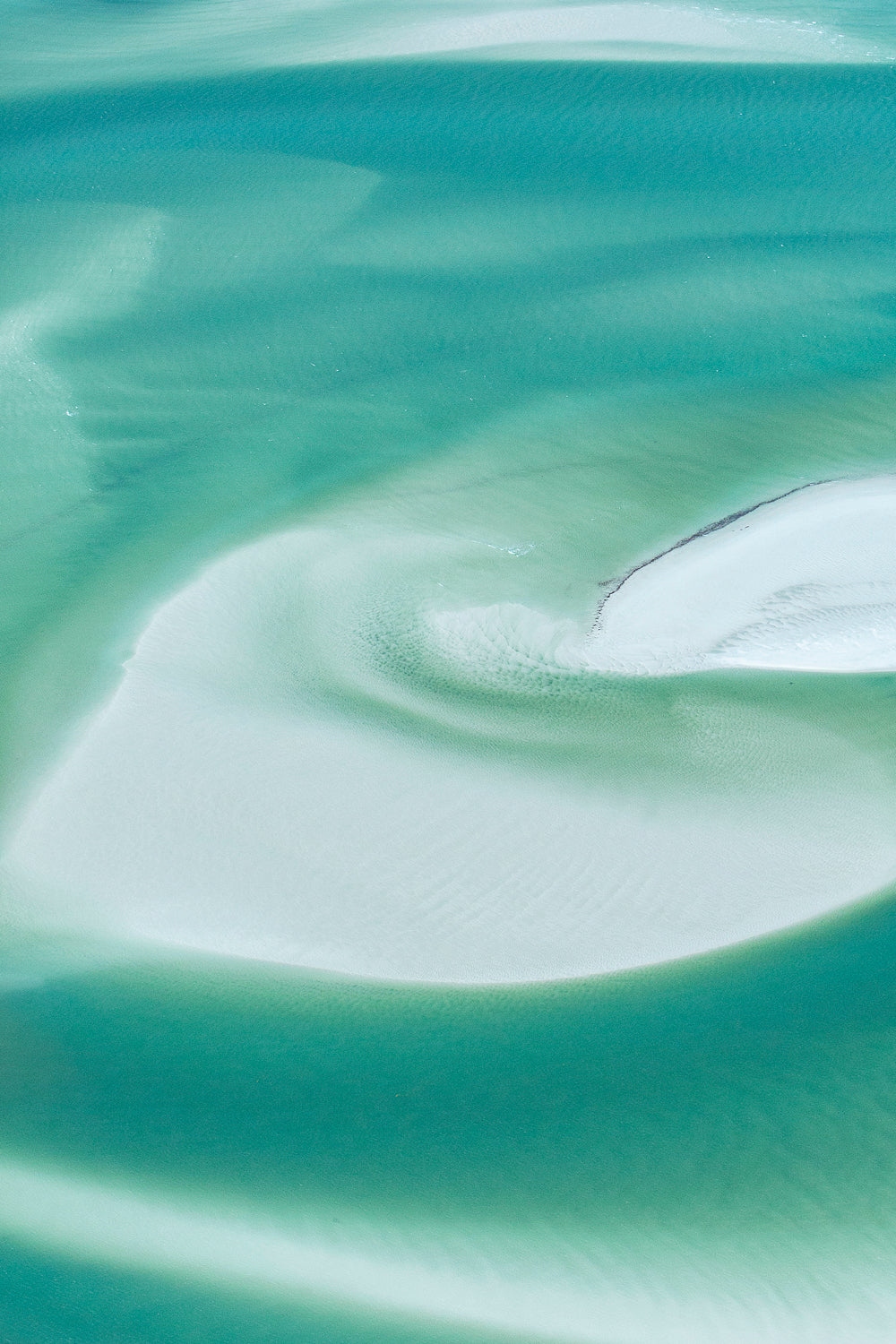 turquiose water swirling amongst white silica sand