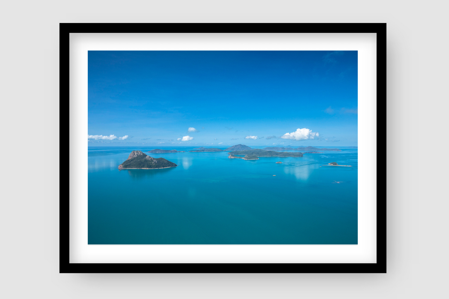 flat blue water below a clear blue sky with islands dotted about
