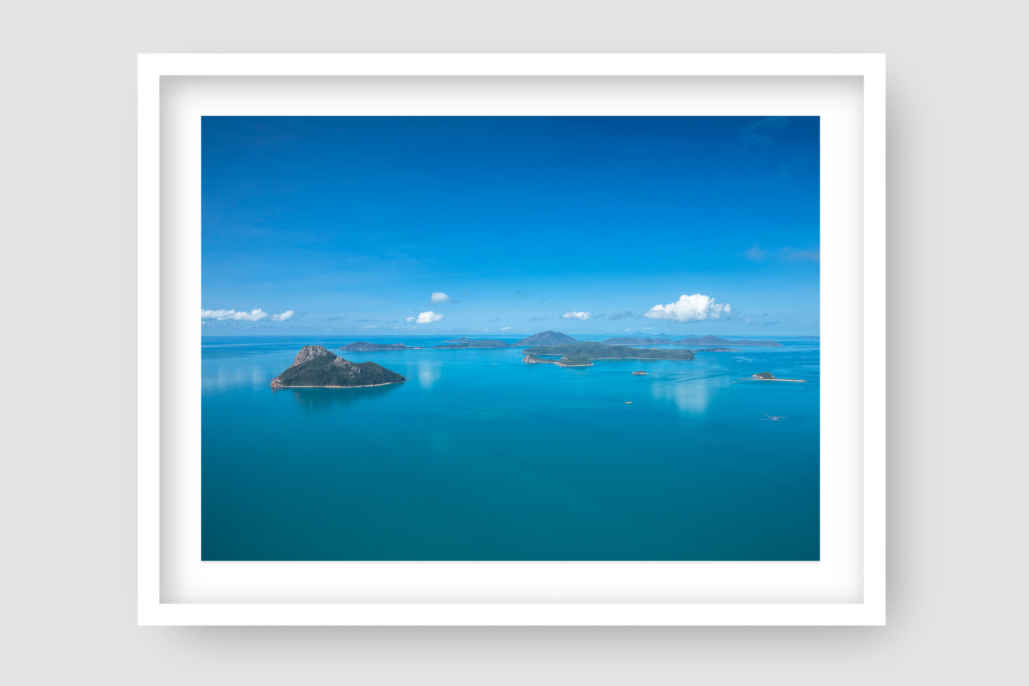 flat blue water below a clear blue sky with islands dotted about