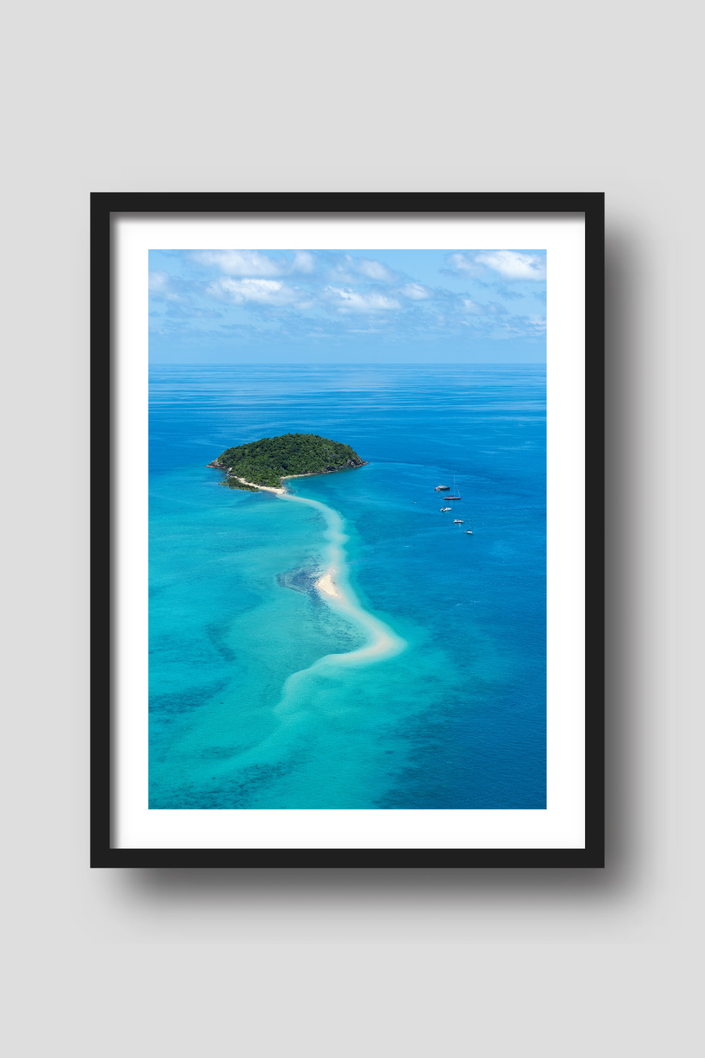 small island with sailing vessels anchored nearby a snaking sandbar through the turquiose waters