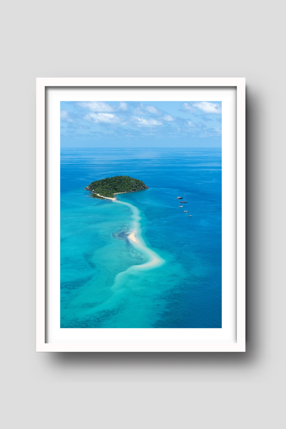 small island with sailing vessels anchored nearby a snaking sandbar through the turquiose waters