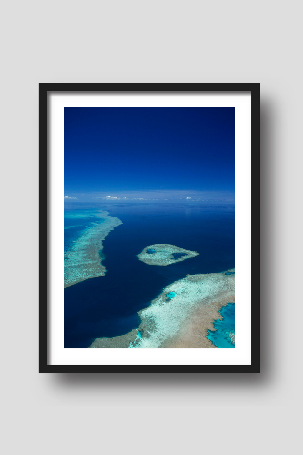 aerial of blue ocean and sky with fringing reef and an island of coral reef creating turquiose coloured water 