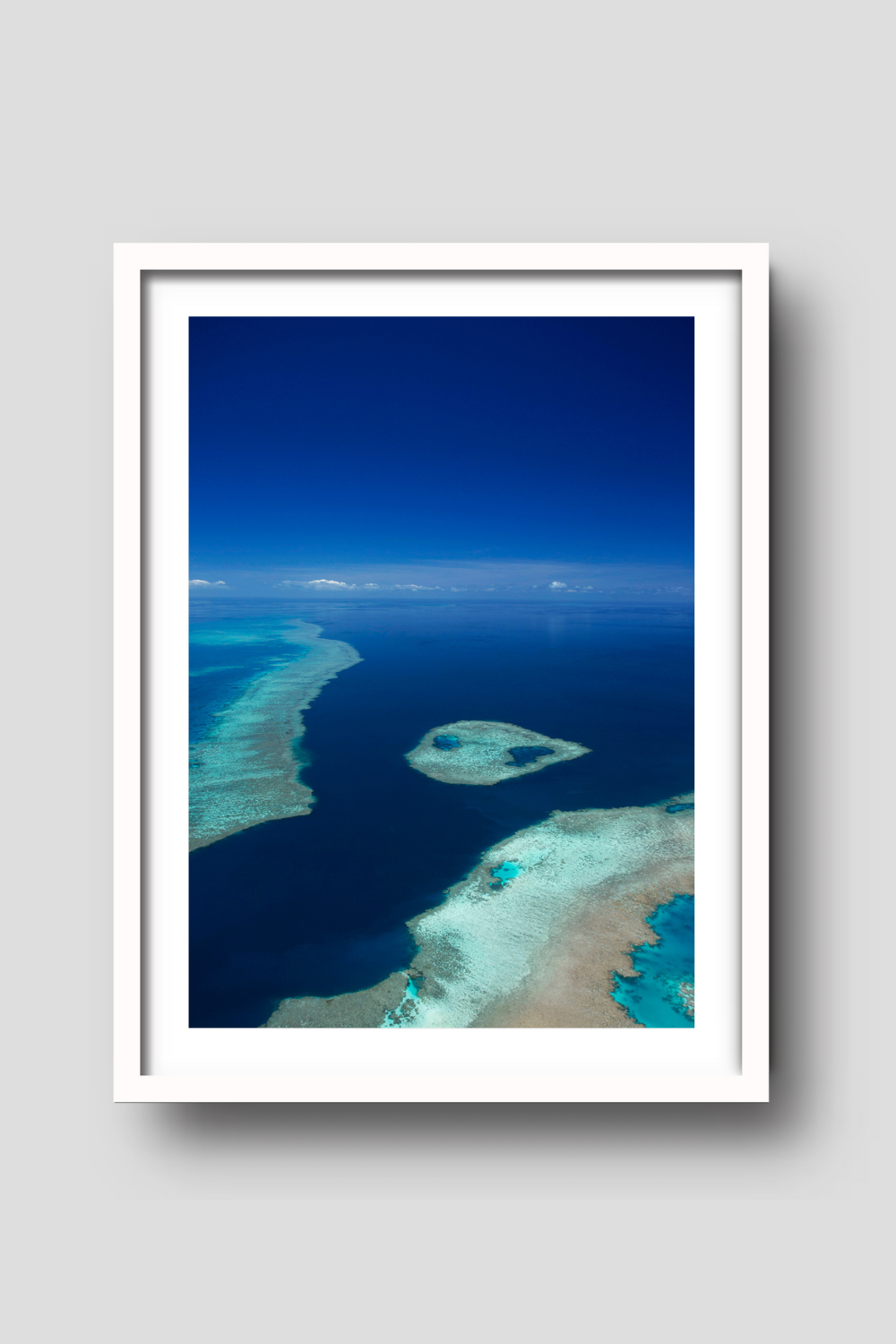 aerial of blue ocean and sky with fringing reef and an island of coral reef creating turquiose coloured water 