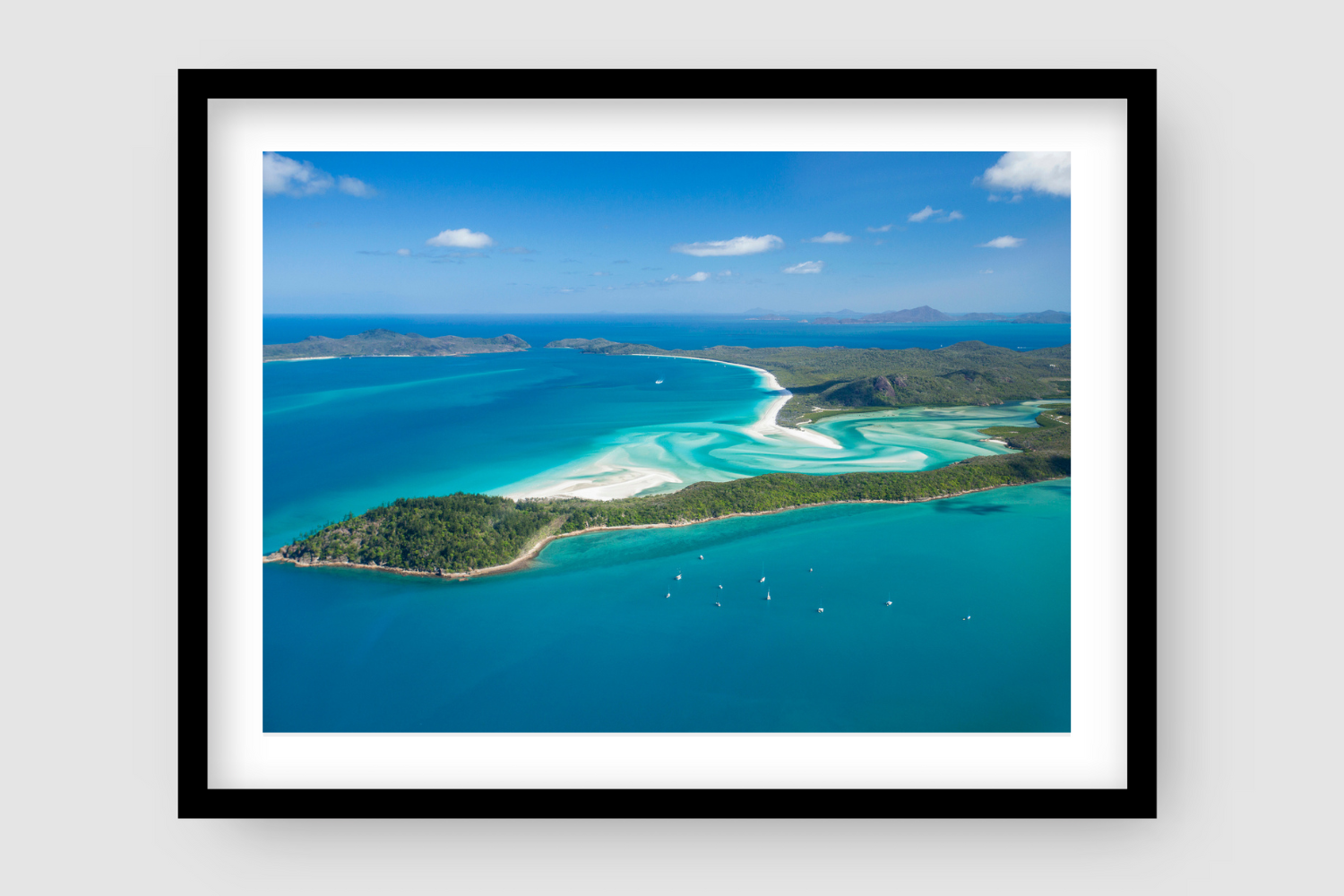 aerial of anchored sailing vessels at a bay with white sand swirling past the bay