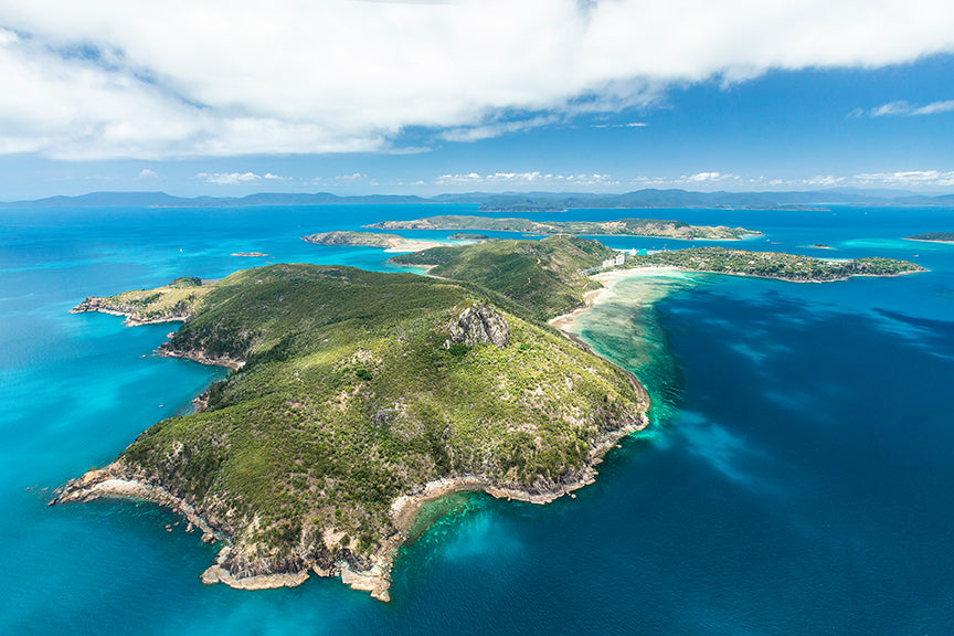 aerial of holiday island looking towards the highest point of the island with green fringing reef